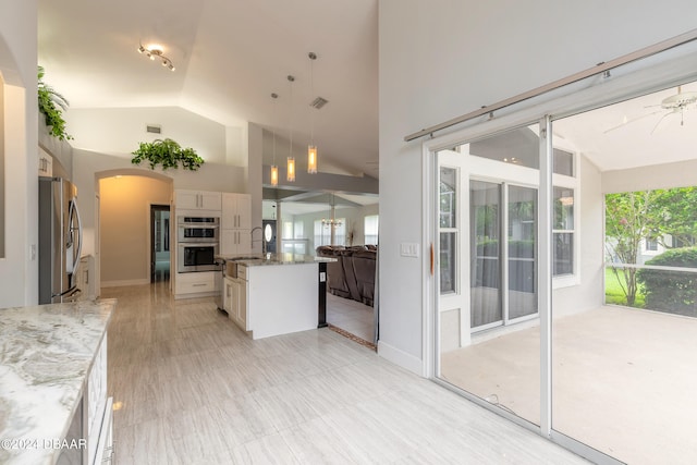 kitchen with white cabinets, hanging light fixtures, an island with sink, and stainless steel appliances