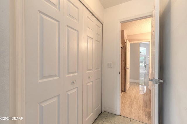 corridor featuring a textured ceiling and light tile patterned floors