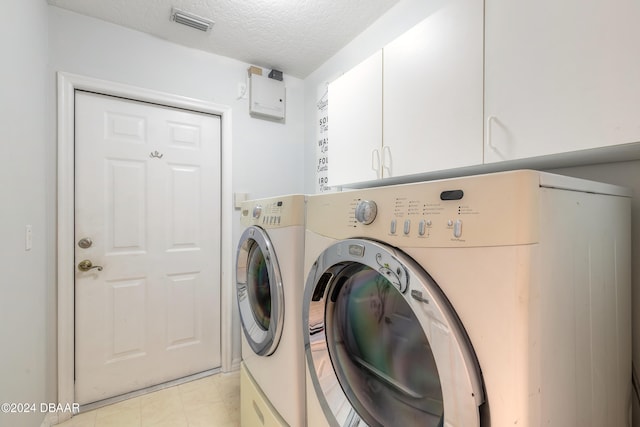 clothes washing area featuring cabinets, independent washer and dryer, and a textured ceiling