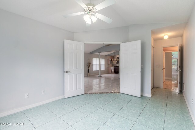 unfurnished room with a wealth of natural light, ceiling fan, light tile patterned floors, and lofted ceiling