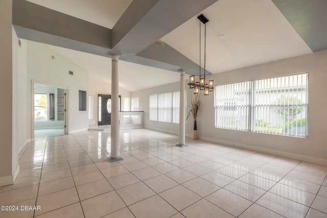 tiled spare room with a healthy amount of sunlight, a notable chandelier, and decorative columns