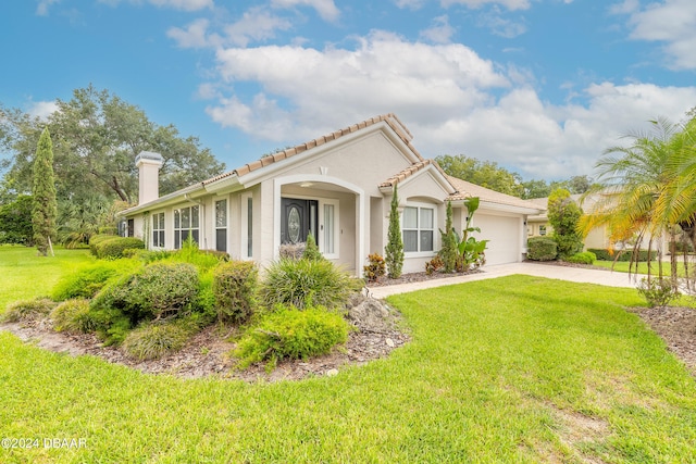 mediterranean / spanish home featuring a front yard and a garage