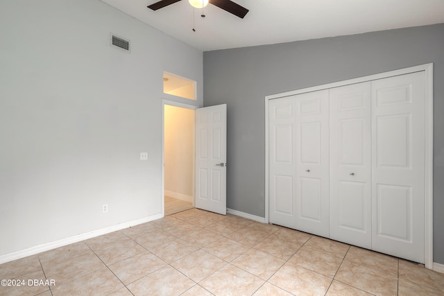 unfurnished bedroom with a closet, lofted ceiling, light tile patterned floors, and ceiling fan