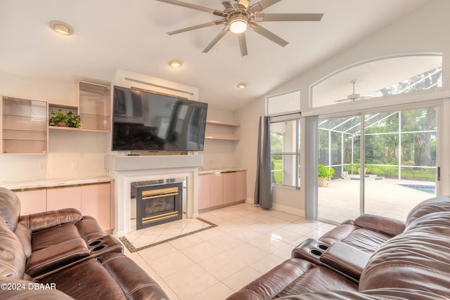 tiled living room featuring a tiled fireplace, ceiling fan, and vaulted ceiling