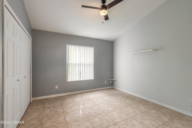 unfurnished bedroom with light tile patterned flooring, ceiling fan, and a closet