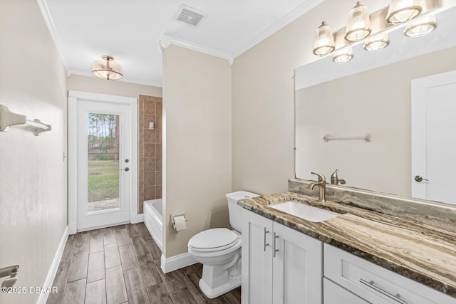 full bathroom featuring crown molding, tiled shower / bath, vanity, and toilet