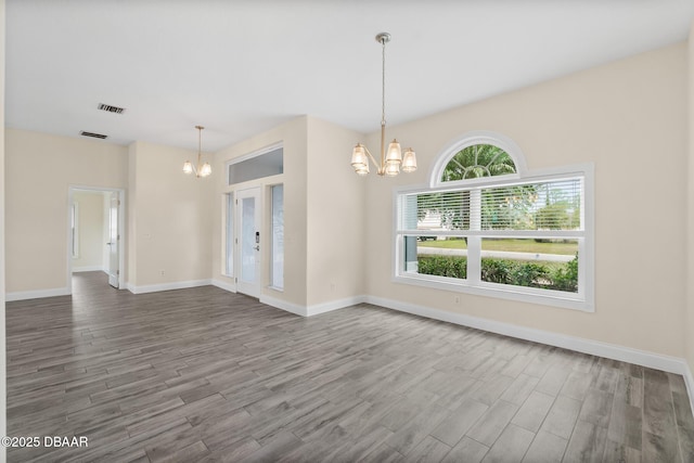 spare room with wood-type flooring and a notable chandelier