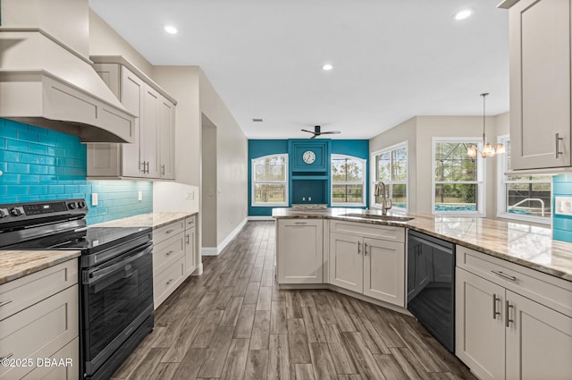 kitchen with premium range hood, light stone countertops, sink, and stainless steel range with electric cooktop