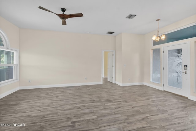 unfurnished room featuring ceiling fan with notable chandelier and light wood-type flooring