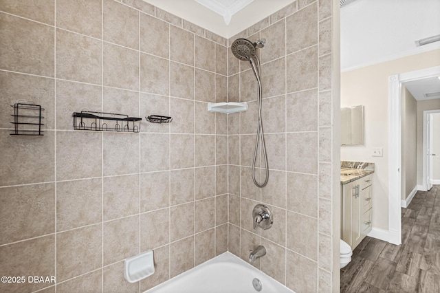 full bathroom with toilet, crown molding, wood-type flooring, vanity, and tiled shower / bath combo