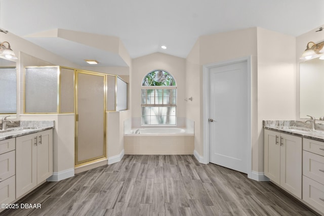 bathroom with wood-type flooring, lofted ceiling, vanity, and separate shower and tub