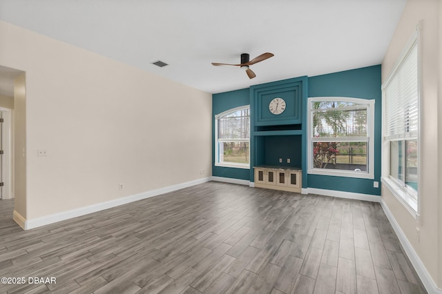 unfurnished living room with hardwood / wood-style floors, a wealth of natural light, and ceiling fan