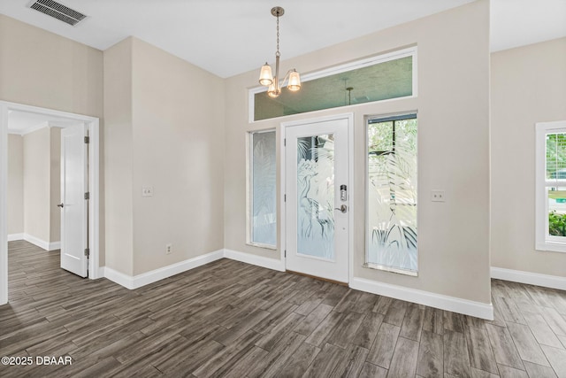 entrance foyer with a healthy amount of sunlight, an inviting chandelier, and dark hardwood / wood-style flooring