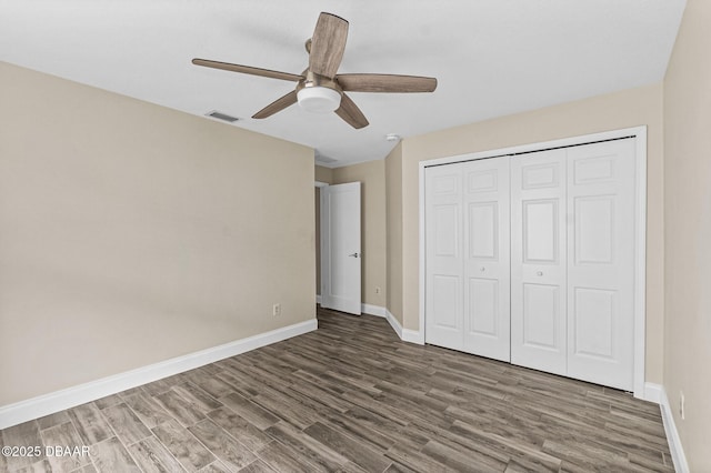 unfurnished bedroom with ceiling fan, dark hardwood / wood-style flooring, and a closet