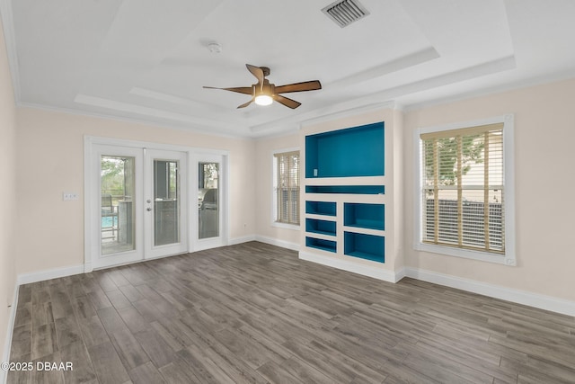 unfurnished living room with hardwood / wood-style floors, crown molding, a raised ceiling, and french doors