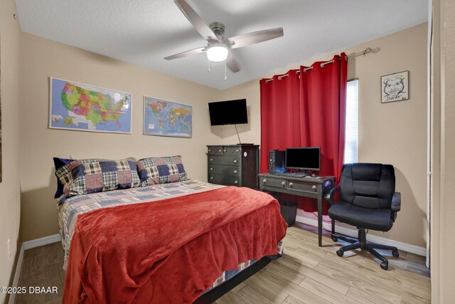 bedroom featuring ceiling fan, a textured ceiling, baseboards, and wood finished floors