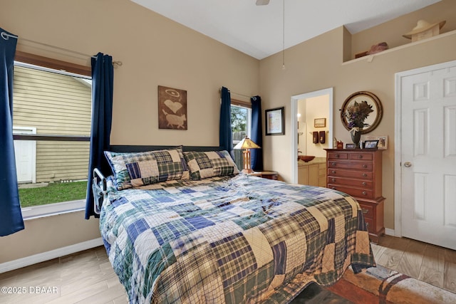 bedroom with ensuite bathroom, a ceiling fan, light wood-style flooring, and baseboards