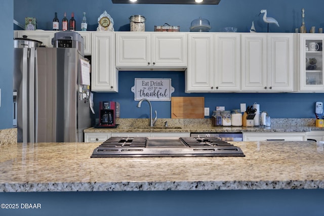 kitchen featuring stainless steel appliances, glass insert cabinets, white cabinetry, and light stone countertops