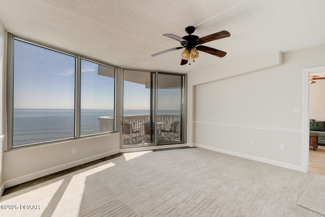 1133 Ocean Shore Blvd Unit 905, Ormond Beach, FL 32176 - carpeted empty room featuring ceiling fan, a textured ceiling, a water view, and baseboards