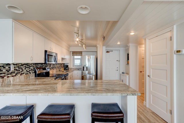 1133 Ocean Shore Blvd Unit 905, Ormond Beach, FL 32176 - kitchen with appliances with stainless steel finishes, ornamental molding, a peninsula, light wood-style flooring, and backsplash