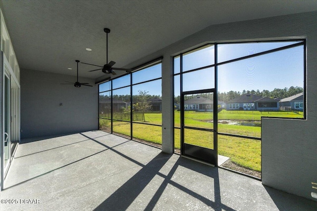 unfurnished sunroom featuring a healthy amount of sunlight, a residential view, and ceiling fan