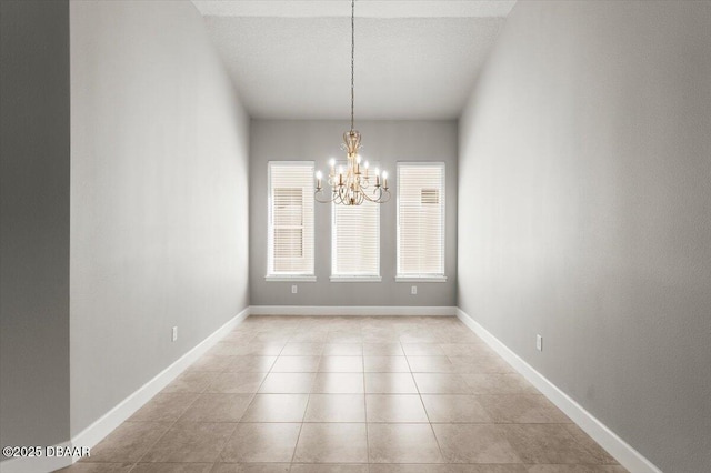 spare room featuring light tile patterned floors, baseboards, a textured ceiling, and an inviting chandelier