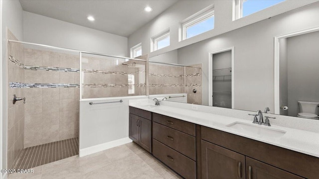 bathroom with a sink, toilet, double vanity, and a walk in shower