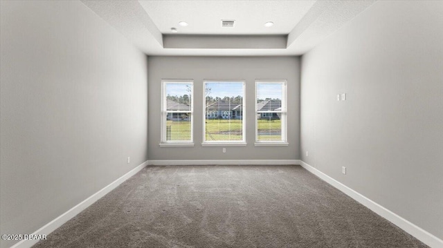 carpeted empty room featuring recessed lighting, visible vents, a raised ceiling, and baseboards