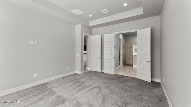 unfurnished bedroom featuring carpet, baseboards, ensuite bath, recessed lighting, and a raised ceiling