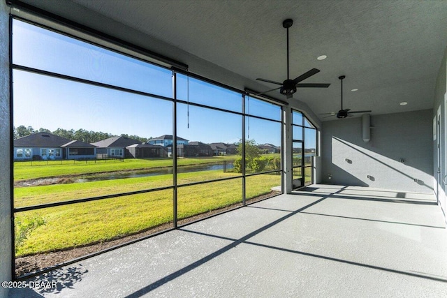 unfurnished sunroom with a residential view, a healthy amount of sunlight, and a ceiling fan