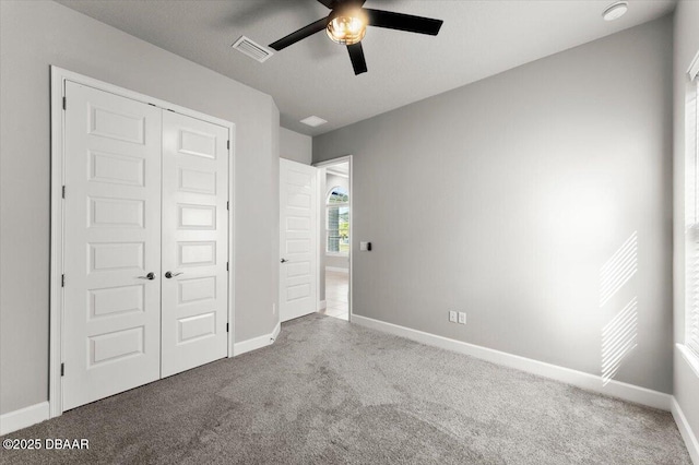 unfurnished bedroom featuring carpet, visible vents, baseboards, ceiling fan, and a closet