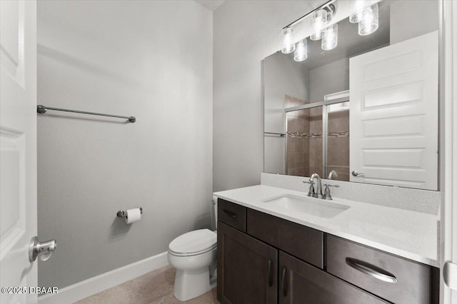 bathroom featuring baseboards, a shower stall, vanity, and toilet