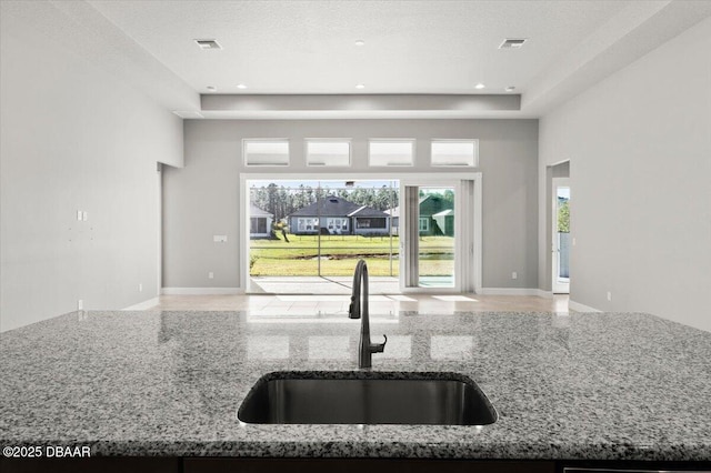 kitchen featuring a sink, visible vents, open floor plan, and a towering ceiling