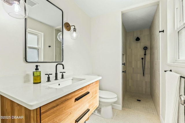 bathroom featuring vanity, toilet, and a tile shower