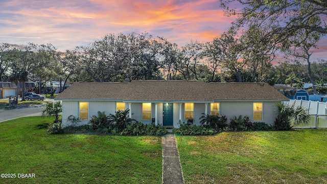 view of front of home with brick siding, fence, and a yard