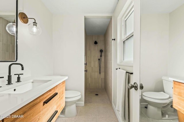 bathroom featuring vanity, toilet, and a tile shower