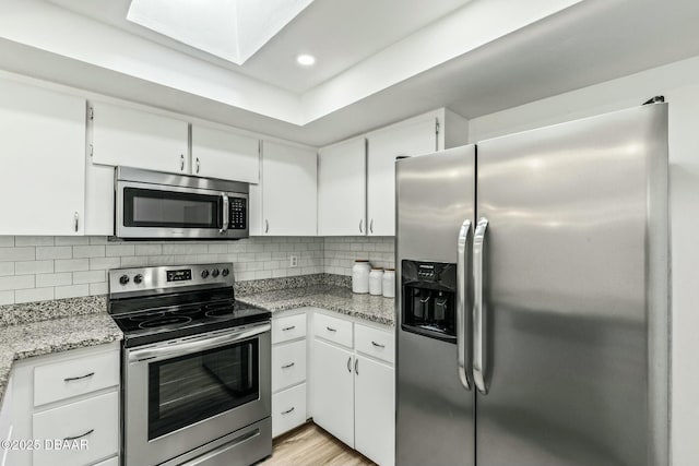 kitchen with backsplash, appliances with stainless steel finishes, light stone counters, and white cabinets