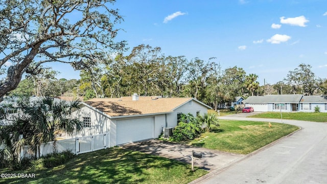 view of side of property with a garage, central AC, and a lawn