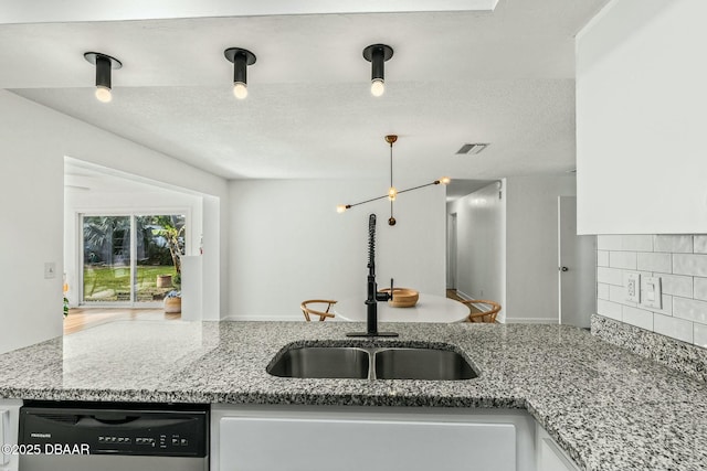 kitchen featuring dishwashing machine, sink, backsplash, light stone countertops, and a textured ceiling