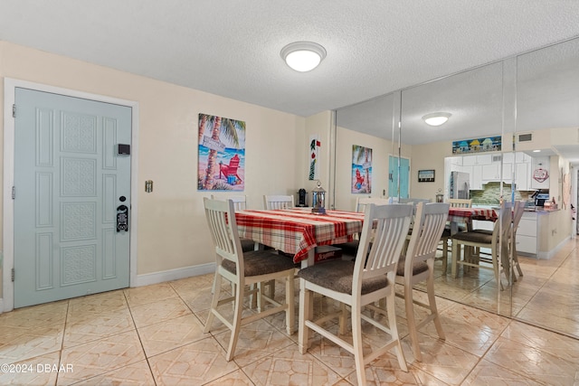 dining space with light tile patterned floors and a textured ceiling