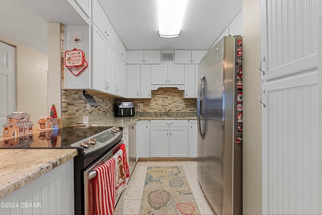 kitchen with tasteful backsplash, white cabinetry, light tile patterned flooring, and appliances with stainless steel finishes