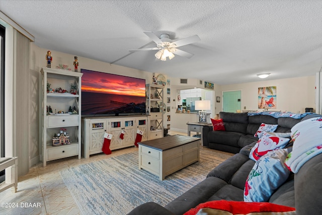 living room with ceiling fan and a textured ceiling