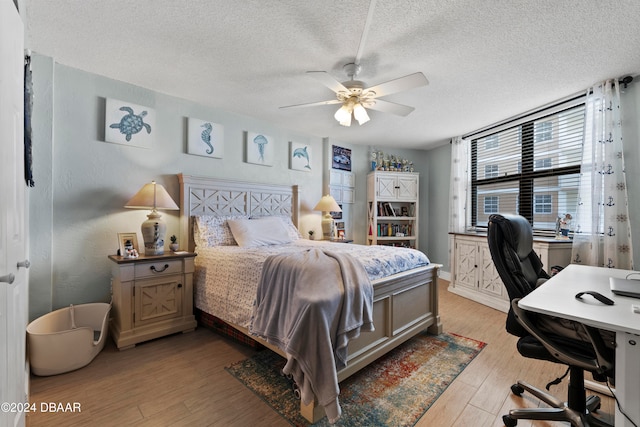 bedroom featuring ceiling fan, light hardwood / wood-style floors, and a textured ceiling