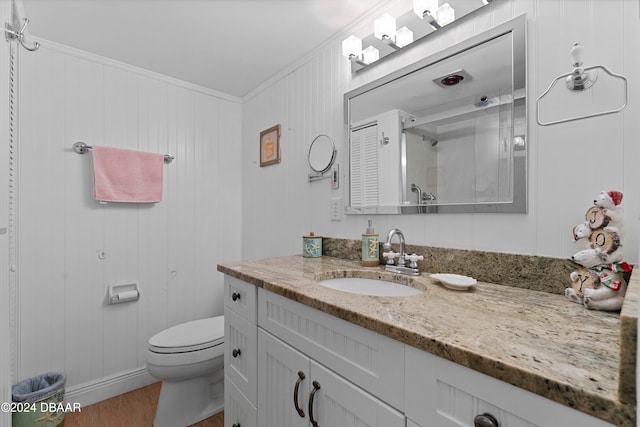 bathroom with vanity, wood walls, crown molding, hardwood / wood-style flooring, and toilet