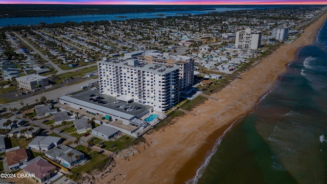 aerial view at dusk with a water view and a view of the beach