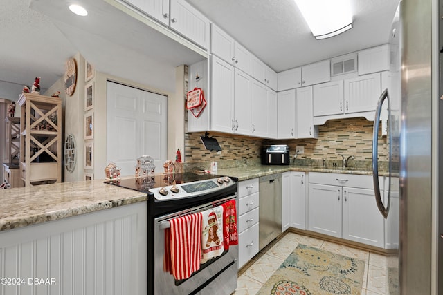 kitchen with tasteful backsplash, light stone counters, white cabinets, and stainless steel appliances