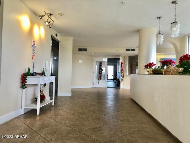 hall featuring dark tile patterned flooring and a chandelier