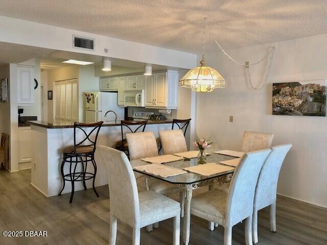 dining room featuring a textured ceiling, dark wood-style flooring, and visible vents