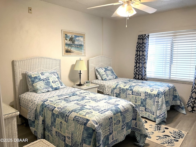 bedroom featuring ceiling fan, a textured ceiling, and wood finished floors