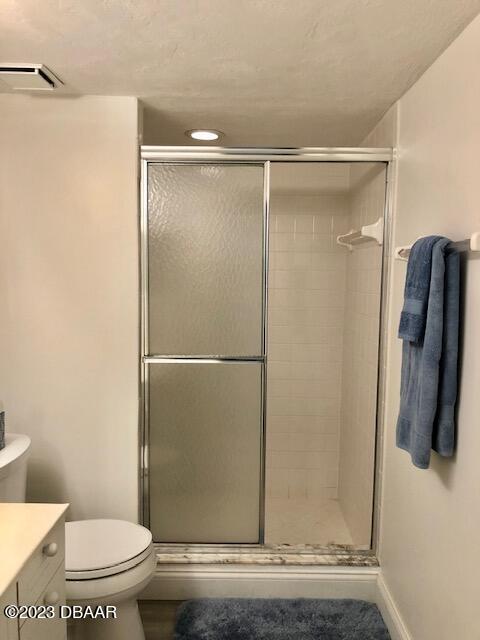 bathroom featuring a shower with shower door, vanity, and toilet